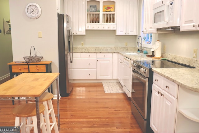 kitchen with light hardwood / wood-style flooring, stainless steel appliances, and white cabinets