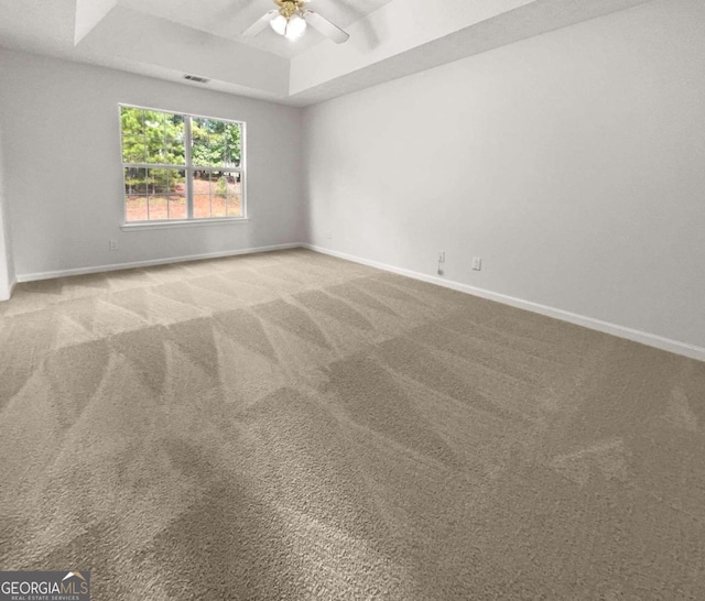 unfurnished room featuring a tray ceiling, ceiling fan, and carpet