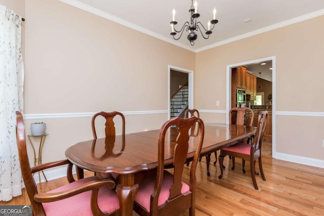 dining room featuring a chandelier, crown molding, and light hardwood / wood-style flooring