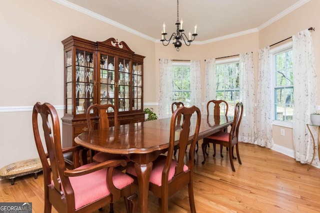 dining area with light wood-type flooring, crown molding, plenty of natural light, and an inviting chandelier