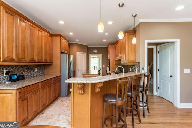 kitchen with crown molding, light wood-type flooring, stainless steel fridge, kitchen peninsula, and pendant lighting