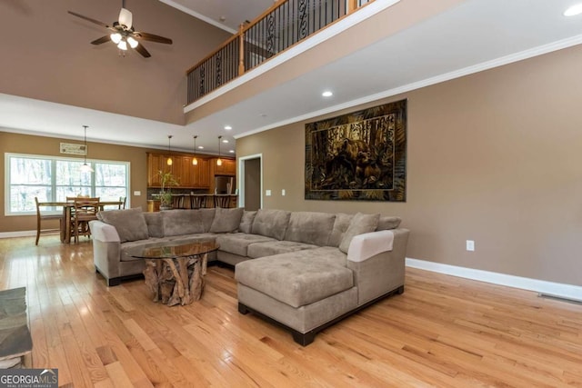 living room with high vaulted ceiling, ceiling fan, light hardwood / wood-style floors, and ornamental molding