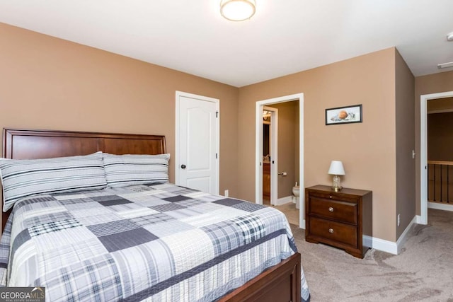 bedroom featuring connected bathroom and light colored carpet