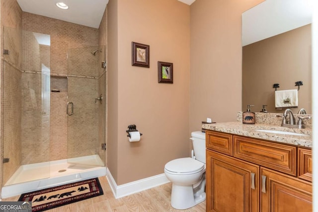 bathroom with an enclosed shower, toilet, hardwood / wood-style flooring, and vanity