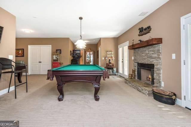 recreation room featuring pool table, light colored carpet, and a stone fireplace