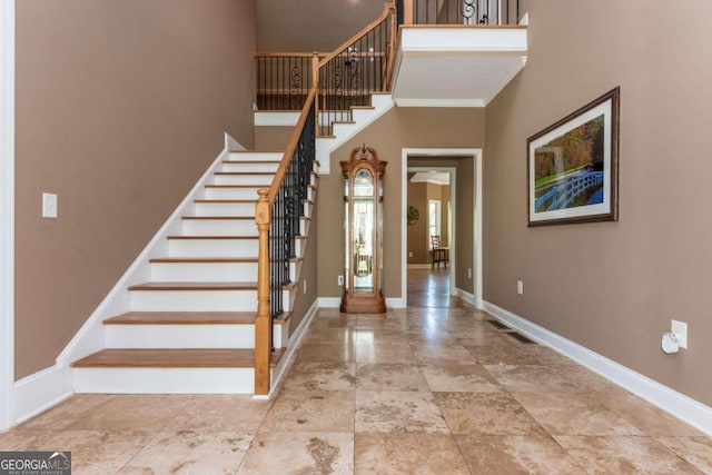 entryway featuring crown molding and a towering ceiling