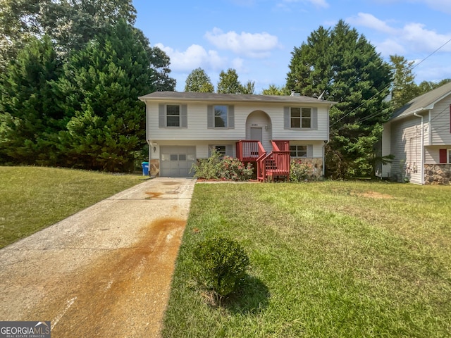 raised ranch featuring stone siding, driveway, an attached garage, and a front lawn