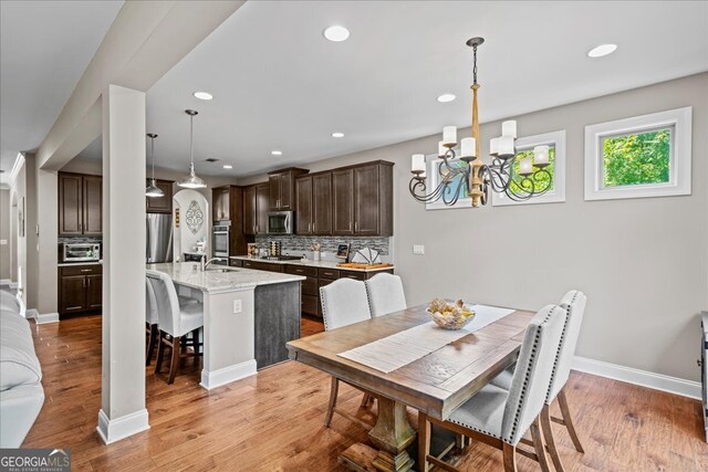 dining room featuring light hardwood / wood-style flooring, sink, and a notable chandelier