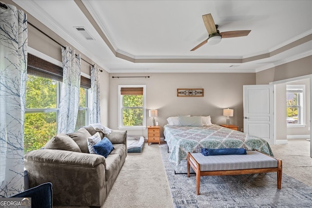 carpeted bedroom with ceiling fan, ornamental molding, and a tray ceiling