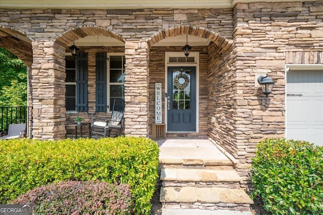 doorway to property with a garage and covered porch