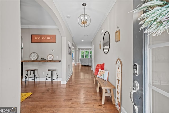 foyer featuring ornamental molding, wood-type flooring, and a notable chandelier