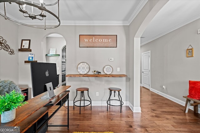 kitchen featuring crown molding, hardwood / wood-style flooring, a breakfast bar area, and a notable chandelier