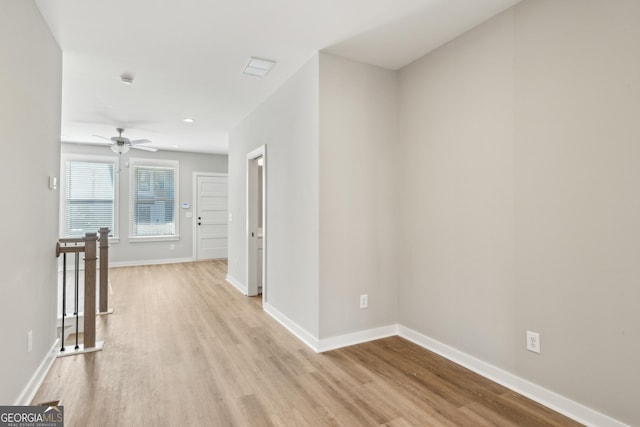 hallway featuring light wood-type flooring, baseboards, and an upstairs landing