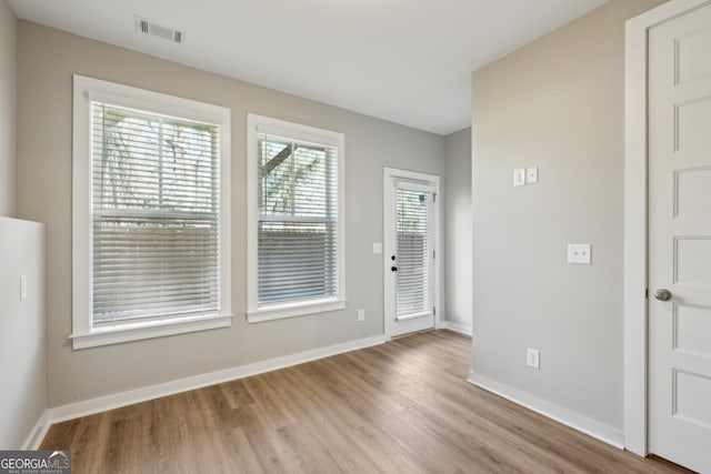 entryway with light wood finished floors, visible vents, and baseboards