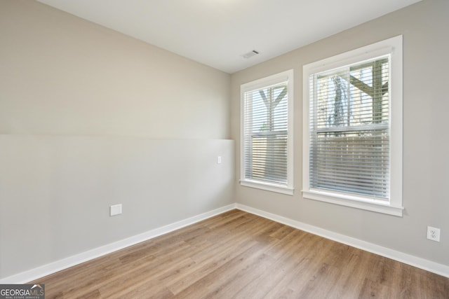 empty room featuring visible vents, light wood-style flooring, and baseboards