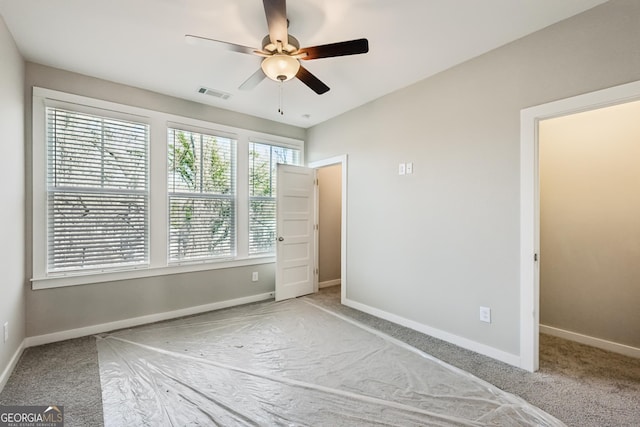 unfurnished bedroom with a ceiling fan, light colored carpet, visible vents, and baseboards