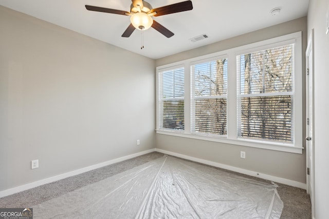 unfurnished room with ceiling fan, visible vents, and baseboards