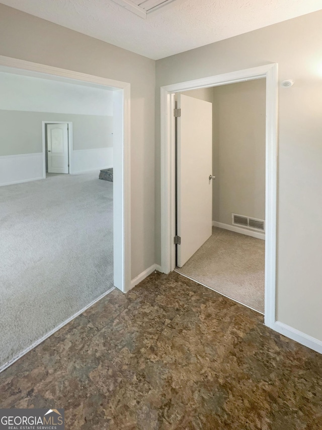 carpeted empty room featuring visible vents and a textured ceiling