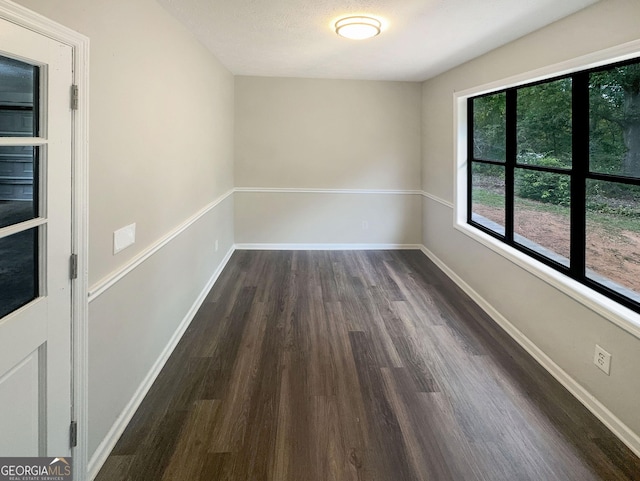 spare room featuring baseboards, dark wood-type flooring, and a textured ceiling