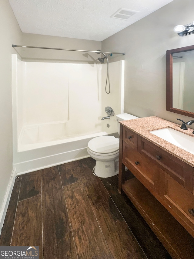 full bathroom with a textured ceiling, vanity, hardwood / wood-style floors, bathing tub / shower combination, and toilet