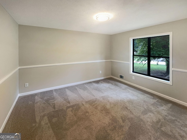 carpeted spare room featuring baseboards, visible vents, and a textured ceiling