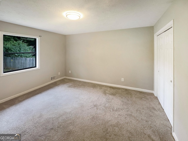unfurnished bedroom featuring visible vents, a textured ceiling, a closet, carpet flooring, and baseboards