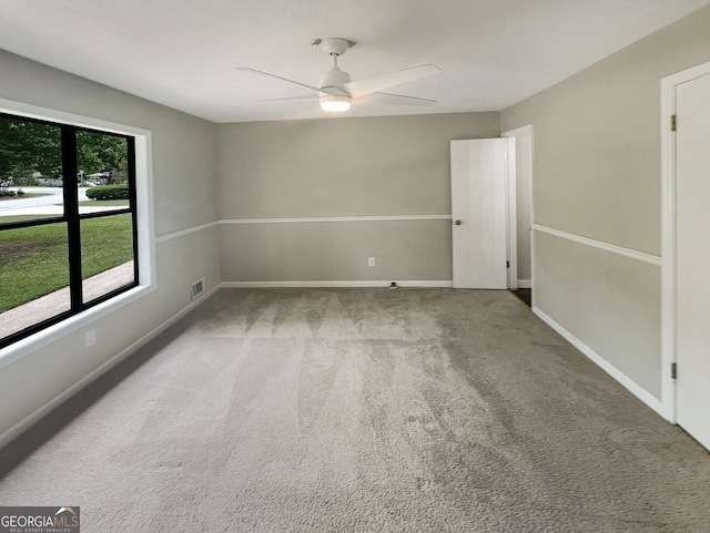 empty room featuring visible vents, carpet floors, baseboards, and ceiling fan