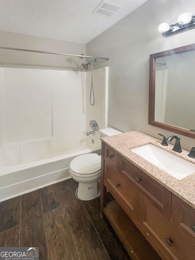 bathroom featuring visible vents, toilet, vanity, wood finished floors, and a textured ceiling