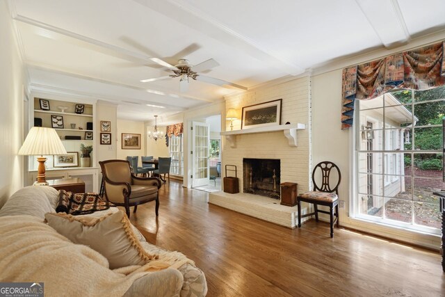 living room with a fireplace, ceiling fan with notable chandelier, a wealth of natural light, and hardwood / wood-style floors