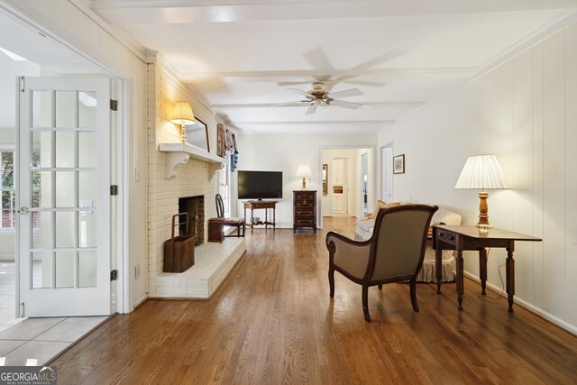 living room featuring a fireplace, beamed ceiling, hardwood / wood-style flooring, and ceiling fan