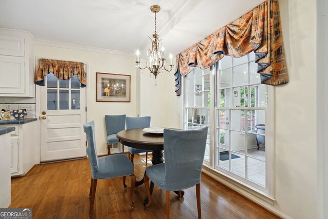 dining space with crown molding, hardwood / wood-style flooring, and a notable chandelier