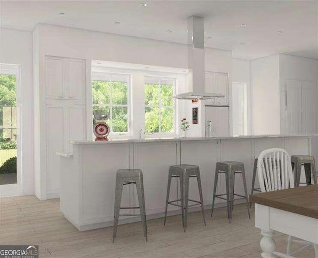 kitchen with white cabinets, a kitchen breakfast bar, a wealth of natural light, and island range hood