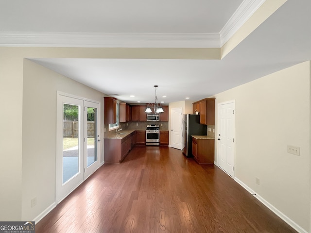 kitchen featuring dark hardwood / wood-style floors, pendant lighting, appliances with stainless steel finishes, ornamental molding, and sink