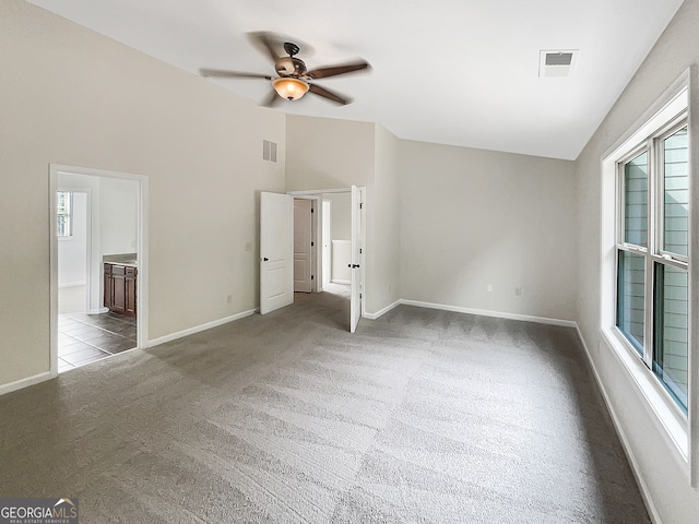 interior space with vaulted ceiling, ensuite bathroom, ceiling fan, and carpet floors