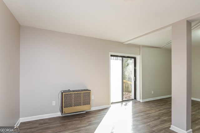 empty room with dark hardwood / wood-style flooring and heating unit