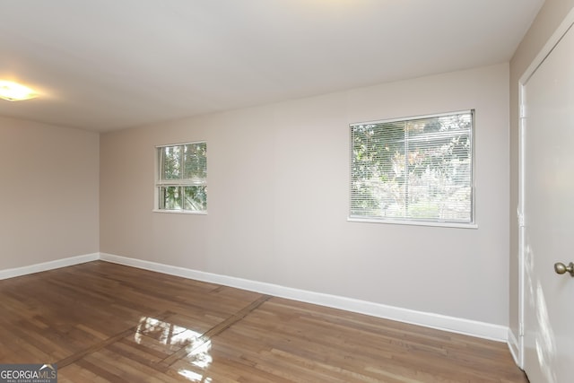 unfurnished room with hardwood / wood-style flooring and a healthy amount of sunlight