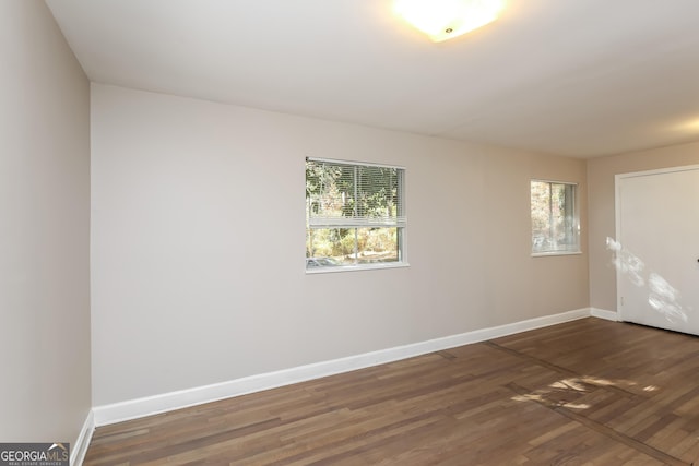 empty room with dark hardwood / wood-style floors and a wealth of natural light