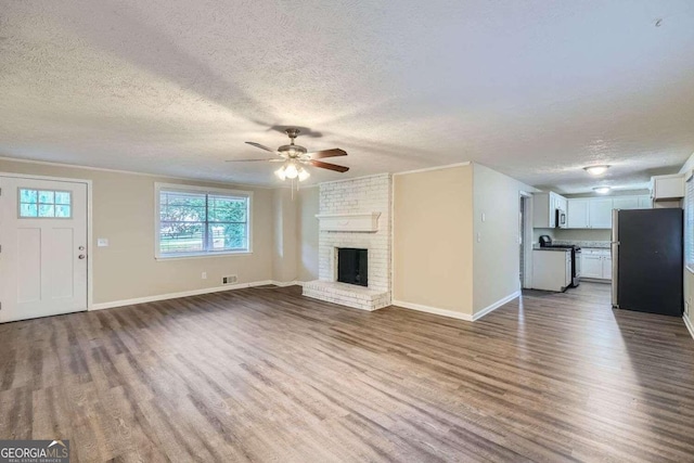 unfurnished living room with a textured ceiling, ceiling fan, dark hardwood / wood-style flooring, and a fireplace