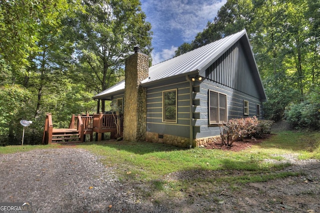 view of side of property with crawl space, metal roof, a chimney, and a wooden deck