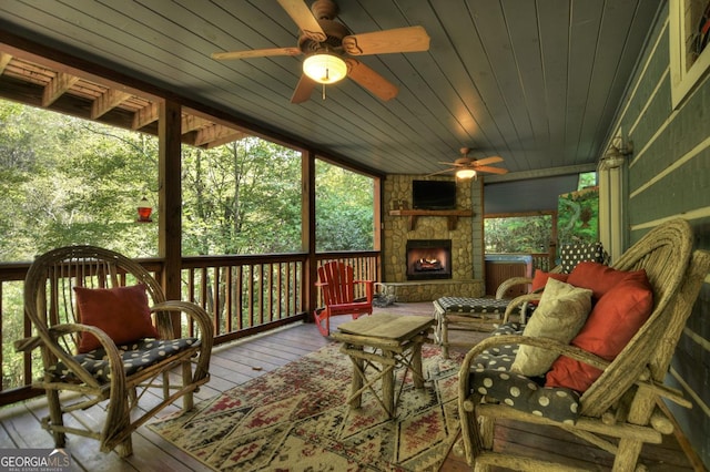 sunroom / solarium with wooden ceiling, ceiling fan, and a stone fireplace