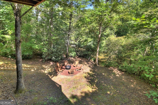 view of yard with a fire pit and a view of trees