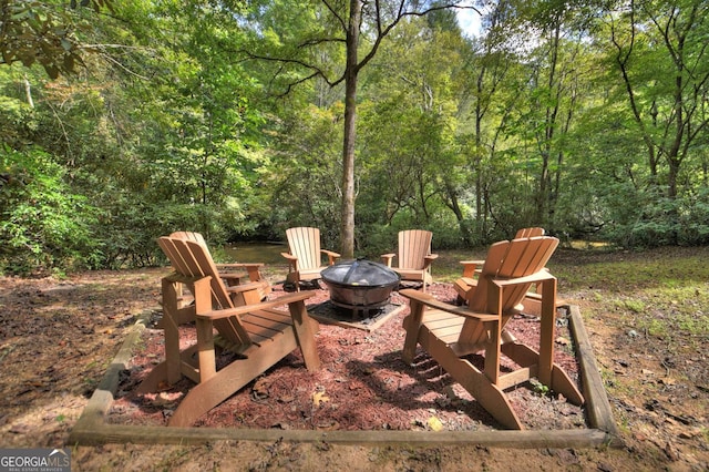 view of patio featuring an outdoor fire pit and a view of trees