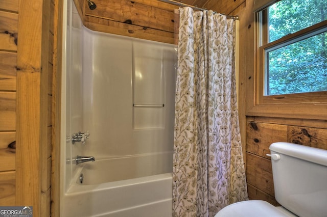 bathroom with shower / bath combination with curtain, wood walls, and toilet