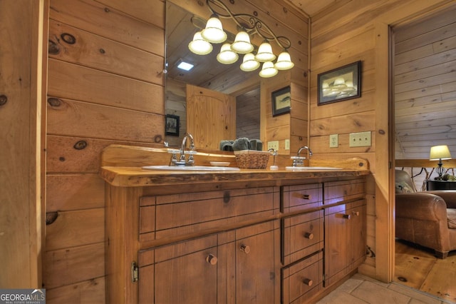 full bathroom with double vanity, wood walls, a sink, and connected bathroom