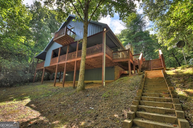 back of house with board and batten siding, stairway, and a deck