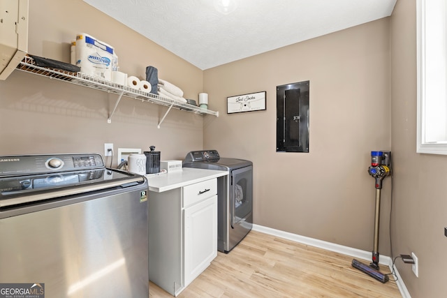 laundry room featuring cabinets, a textured ceiling, washing machine and clothes dryer, electric panel, and light hardwood / wood-style floors