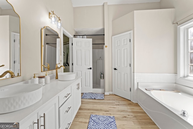 bathroom with independent shower and bath, a wealth of natural light, wood-type flooring, and vanity