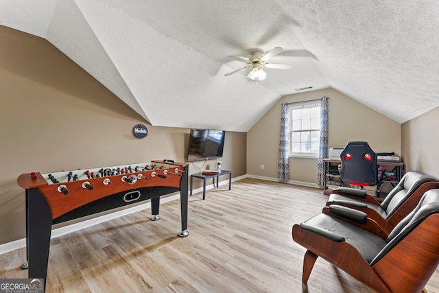 playroom with light wood-type flooring, a textured ceiling, ceiling fan, and lofted ceiling