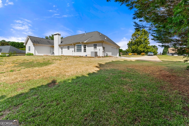 back of property featuring cooling unit, a yard, and a garage