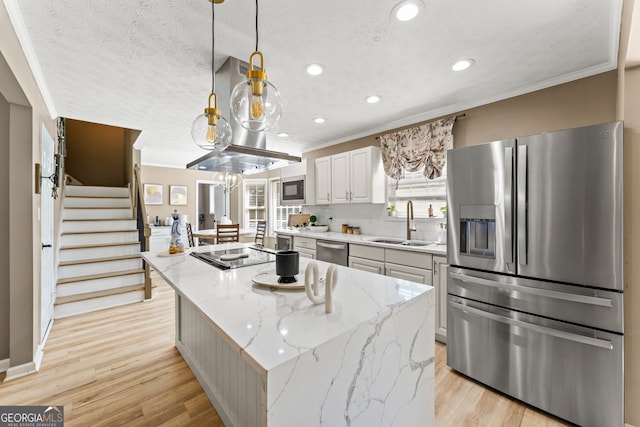 kitchen with white cabinets, decorative light fixtures, stainless steel appliances, sink, and a kitchen island